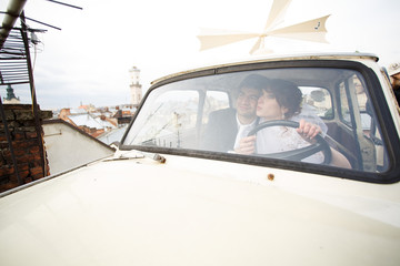 Obraz premium Happy stylish newlywed couple posing in retro car