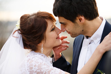 Groom's tender hands touch bride's face while she smiles to him