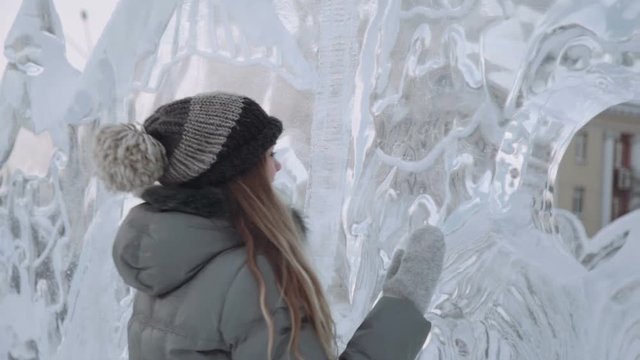 young woman smiling at the ice sculptures, winter gloves
