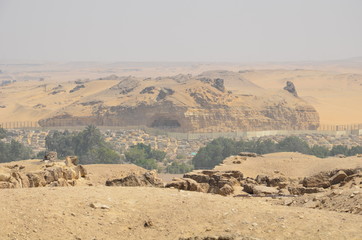 Pyramid in sand dust under gray clouds