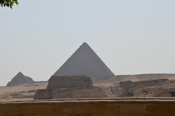 Naklejka na ściany i meble Pyramid in sand dust under gray clouds