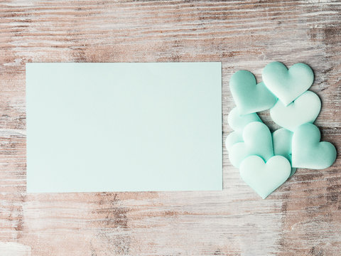 Green pastel hearts and blank card on wooden table. Valentine's mother day or baby birthday greeting card wedding invitation