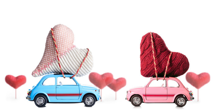 Couple of retro toy cars delivering craft hearts for Valentine's day on white background