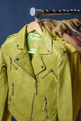Many colored  leather jacket hanging on rack on blue background