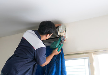 Asian Male Technician Cleaning Air Conditioning System at home