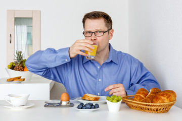 Fototapeta na wymiar Mann trinkt Orangensaft zum Frühstück