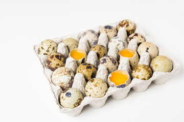 Raw quail eggs on the paper container on the white background