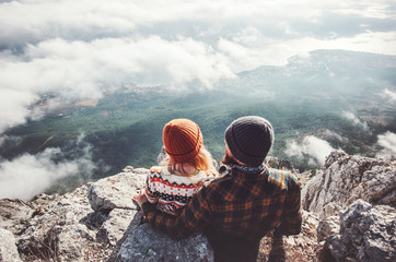 Couple Man and Woman sitting hugging on cliff enjoying mountains and clouds landscape Love and...