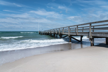 Fototapeta na wymiar pier with stormy sea under blue sky with scattered clouds