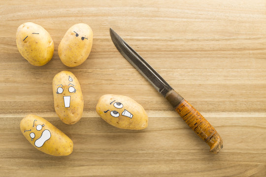 scary face potatoes and knife on wooden cutting board