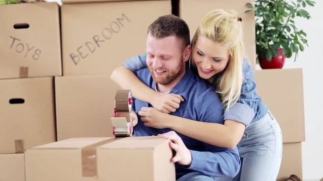 Couple moving into new apartment. Lot of packing cartons around them.