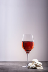 Glass of red wine with white macarons on wooden table