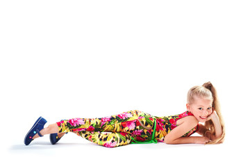 Obraz premium Pretty blondie six years old small girl on white background laying down in colorful cloths and smiling