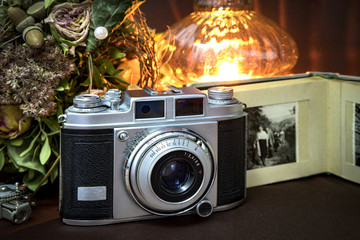 Alte Kamera mit Fotoalbum, Blumen und Kerzenlicht