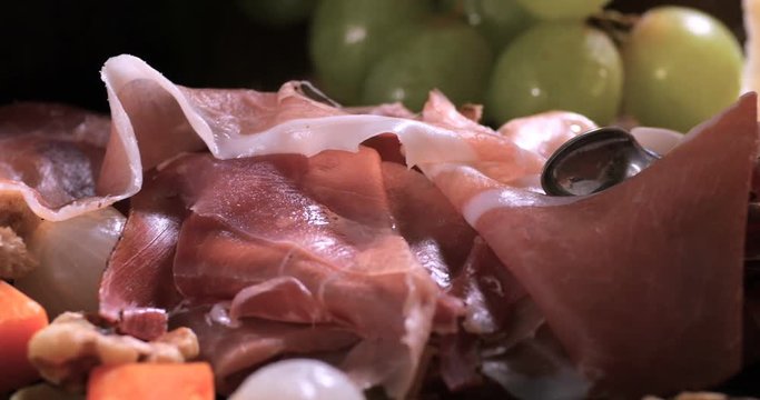 Dolly close up panning view of a platter of cured meat (charcuterie), ham, salami, pate and cheese