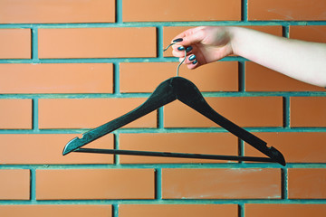Fototapeta na wymiar plastic fashion hanger in female hand in wardrobe
