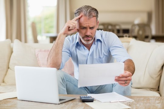 Tense Man Looking At Bills In Living Room