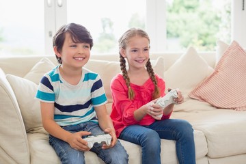 Siblings playing video games in living room