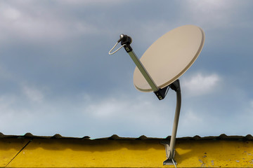 Satellite dish and TV antennas on the old house roof with blue s