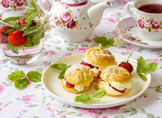 Profiterole or cream puff cakes or filled with whipped cream,g served with strawberries