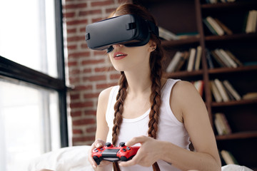 Concept of technology and lifestyle. Young and beautiful girl playing a video game in the virtual...