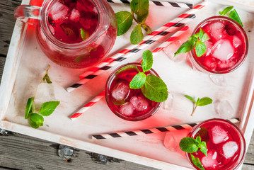 Summer iced drink - tea or juice with ice and mint. On rustic wooden table, with white tray, copy space, top close view © ricka_kinamoto
