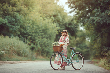 Pregnant girl retro French style with bicycle on a forest road