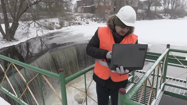 Engineer with laptop checking floodgate