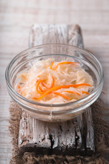 Sauerkraut with carrots in a bowl on the old stand close-up