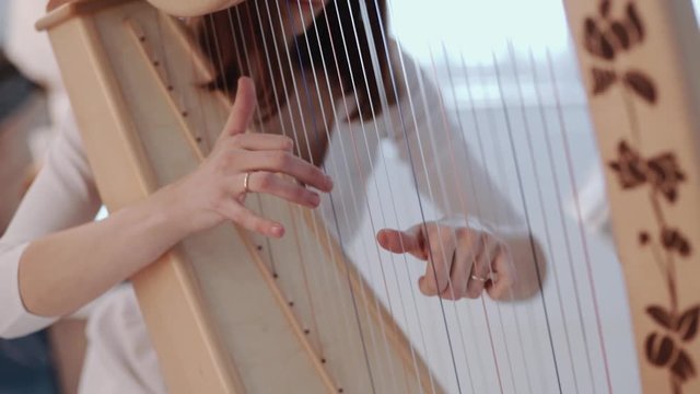 Hands of woman playing a harp. Harpist with classical music instrument. Harp strings close up.