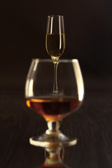 Glasses with white wine and cognac or whisky on mirror table. Celebrities composition.