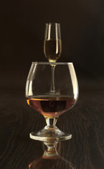 Glasses with white wine and cognac or whisky on mirror table. Celebrities composition.