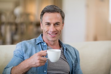 Portrait of smiling man having coffee in living room