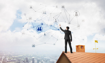 Businessman on house roof presenting networking and connection concept. Mixed media