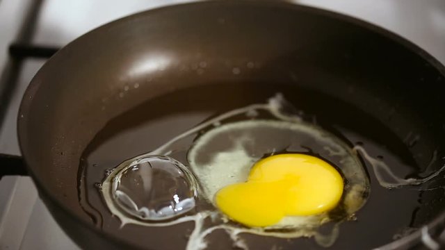 Shot of Breaking egg and cooking scrambled eggs on a hot frying pan