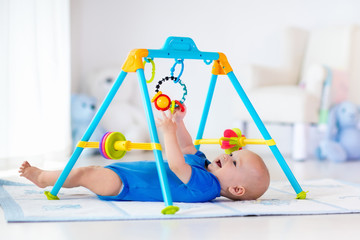 Baby boy on play mat. Child playing in gym. - obrazy, fototapety, plakaty