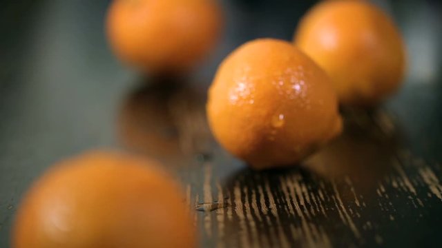closeup dolly shot of organic tangerines on black wood table. Orange fruit on a wooden background