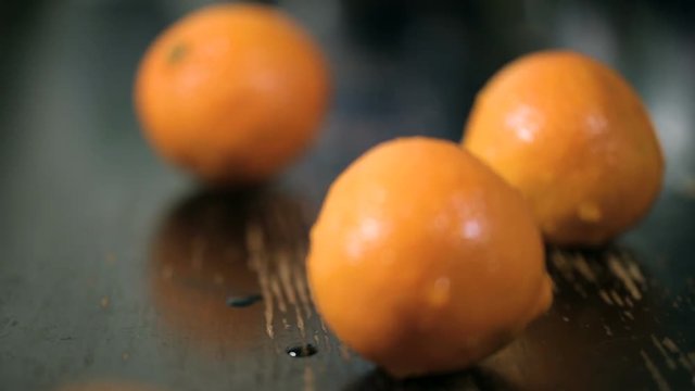 closeup dolly shot of organic tangerines on black wood table. Orange fruit on a wooden background