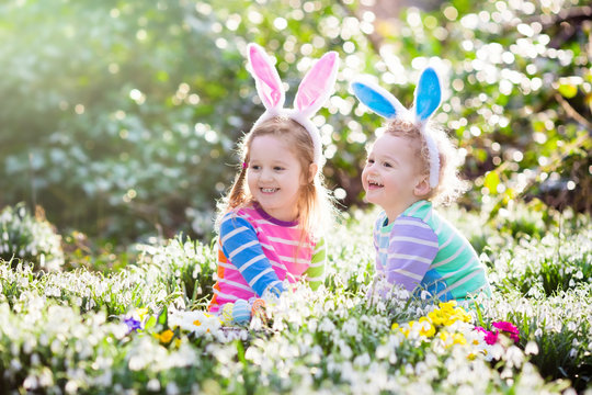 Kids on Easter egg hunt in blooming spring garden