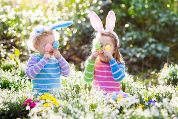 Kids on Easter egg hunt in blooming spring garden
