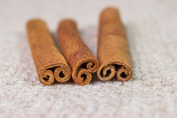 three cinnamon sticks on sacking close-up