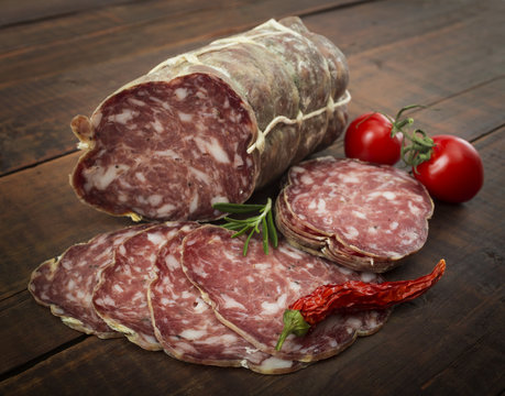 Italian salami with red pepper cherry tomatoes on a wooden background