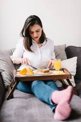 Obraz na płótnie Canvas Girl lying on the couch eating a healthy breakfast
