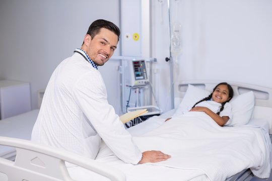 Portrait of doctor and girl patient in hospital bed