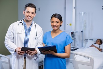 Portrait of doctor and nurse using digital tablet and clipboard