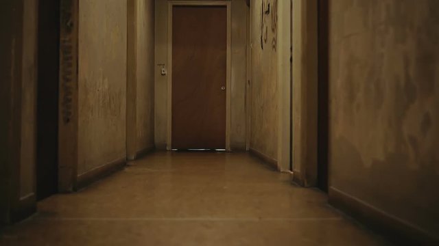 Walking inside a long dark hallway of old apartment building.