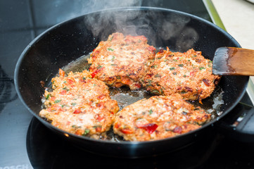 cooking home made meatballs with vegetables in pan on ceramic stove