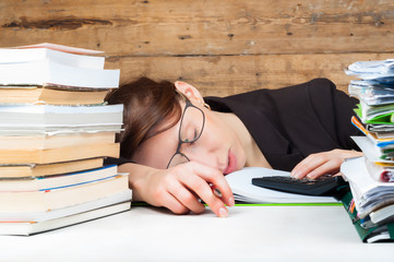 Woman got tired of working and studying next to the stack of papers and books. Work and study...