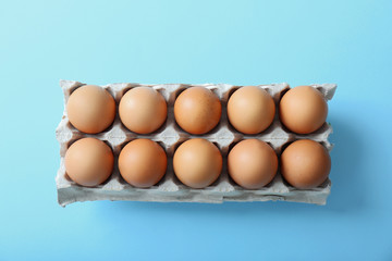 Raw eggs in package on blue background