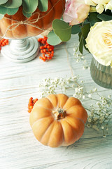 Pumpkin and fresh flowers on white wooden table
